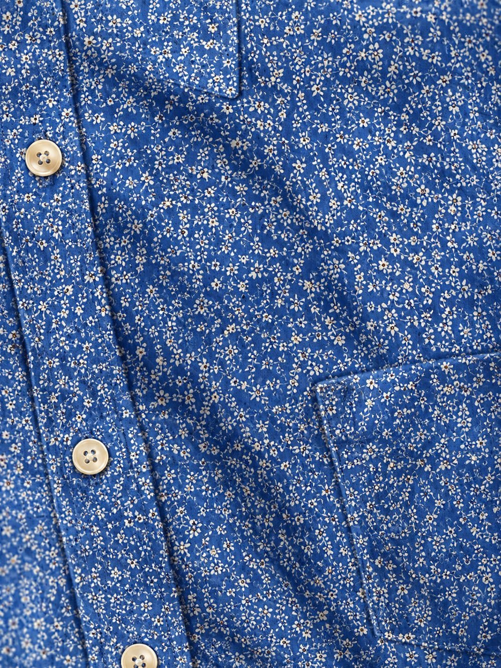 Close-up of a blue floral-print shirt fabric with natural buttons