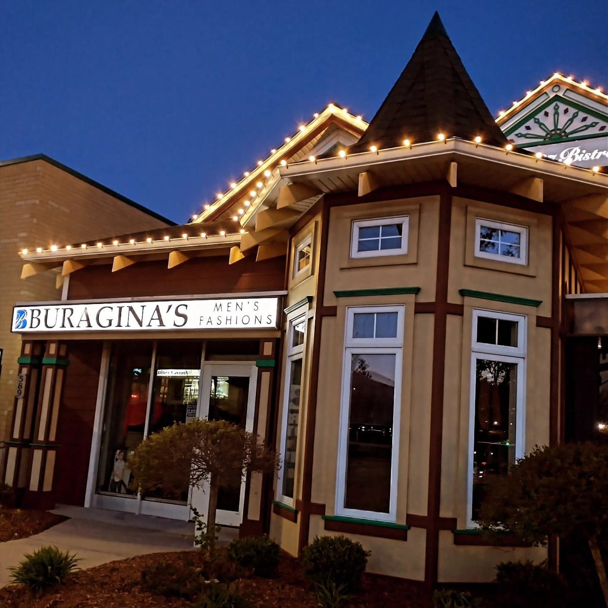 Buragina's Men's Fashions storefront at dusk, lit with string lights
